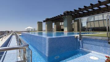 A rooftop swimming pool with a clear view of the city skyline.