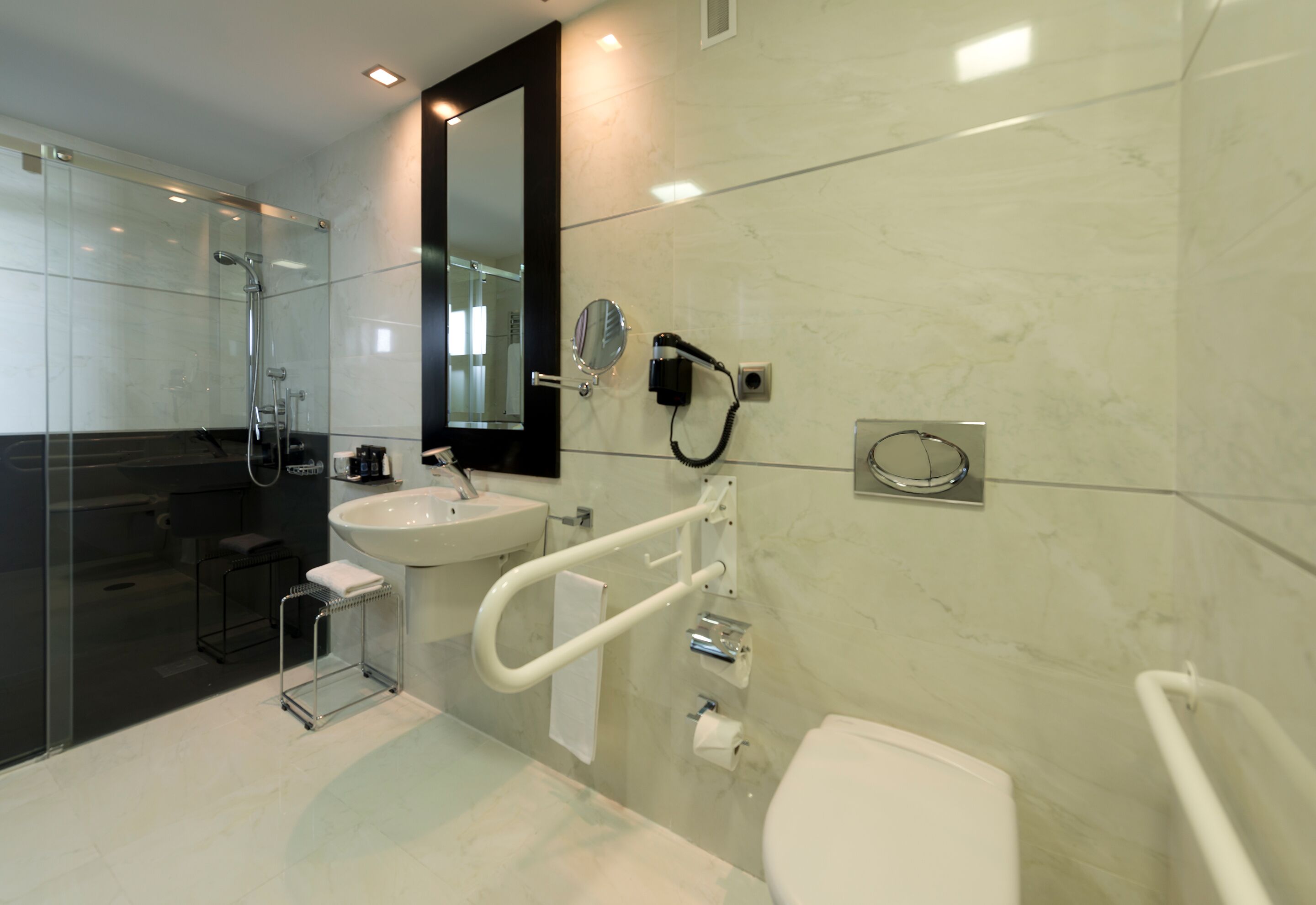 Un baño moderno con cabina de ducha de vidrio, lavabo blanco, espejo y retrete.