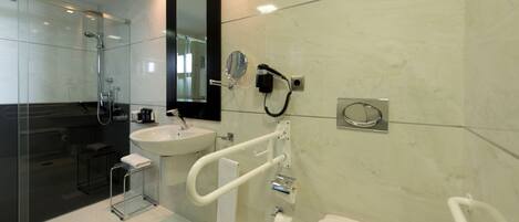 Un baño moderno con cabina de ducha de vidrio, lavabo blanco, espejo y retrete.