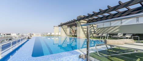 Una piscina al aire libre de temporada, sombrillas, tumbonas