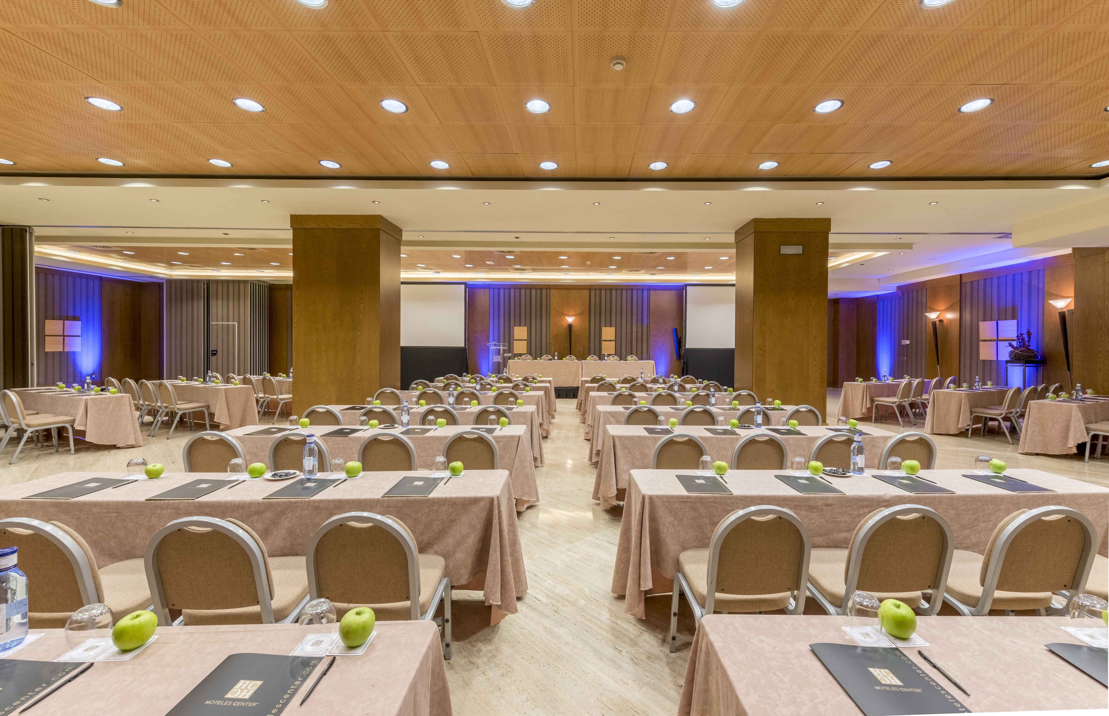 A conference room with rows of tables, chairs, and water bottles.