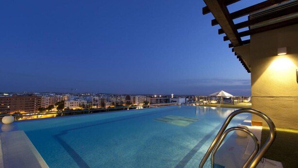 Una piscina al aire libre con vistas a la ciudad al anochecer.