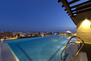 An outdoor swimming pool with a view of the city at dusk. - Hotel Córdoba Center (Córdoba)