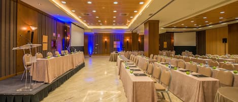 A conference room with a stage, multiple tables, and chairs.