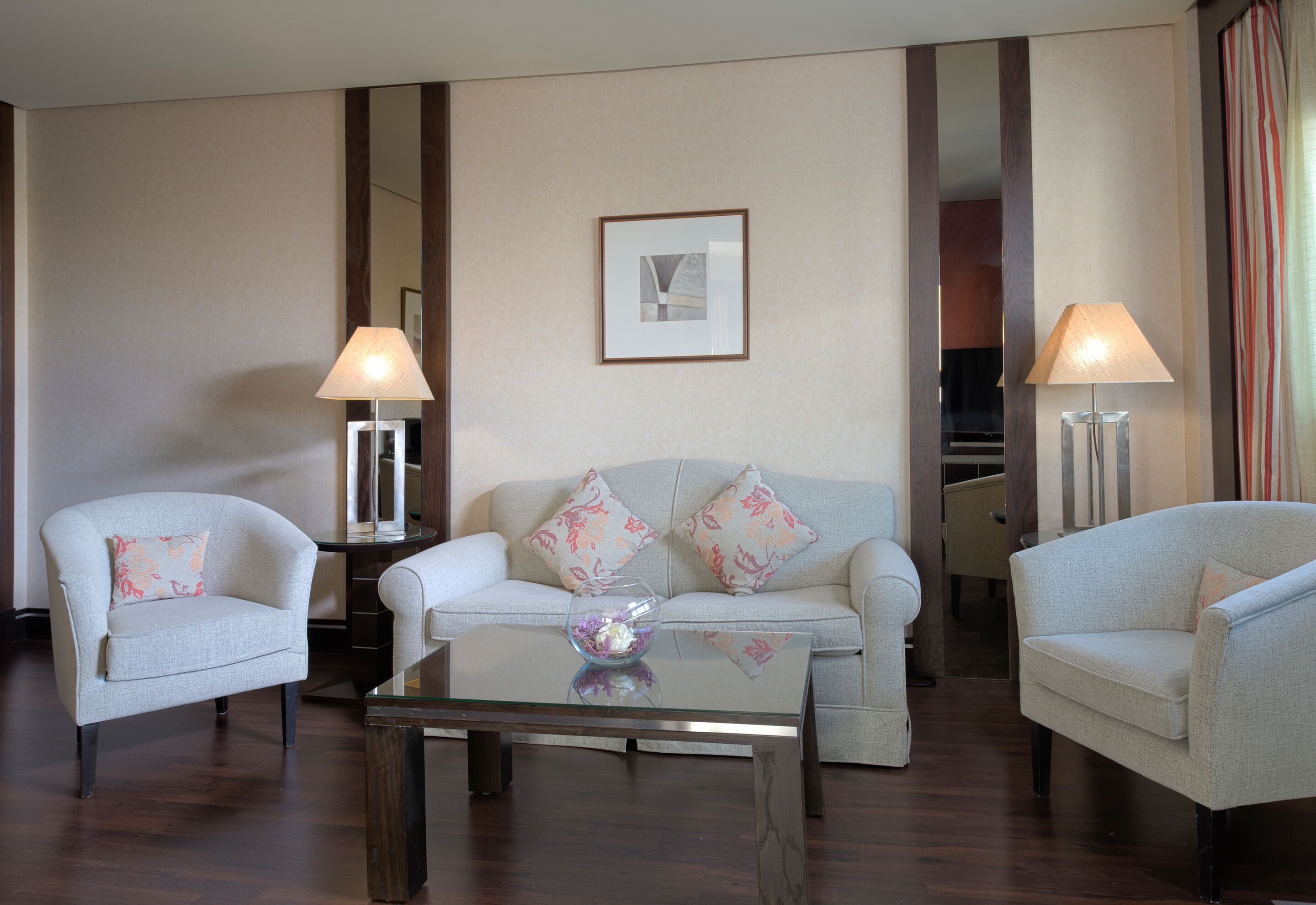 A hotel room with a sofa, two armchairs, a coffee table, and two lamps.