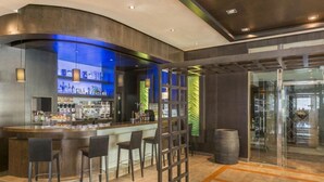 Un área de bar moderna con una barra curva, taburetes y una partición de vidrio.