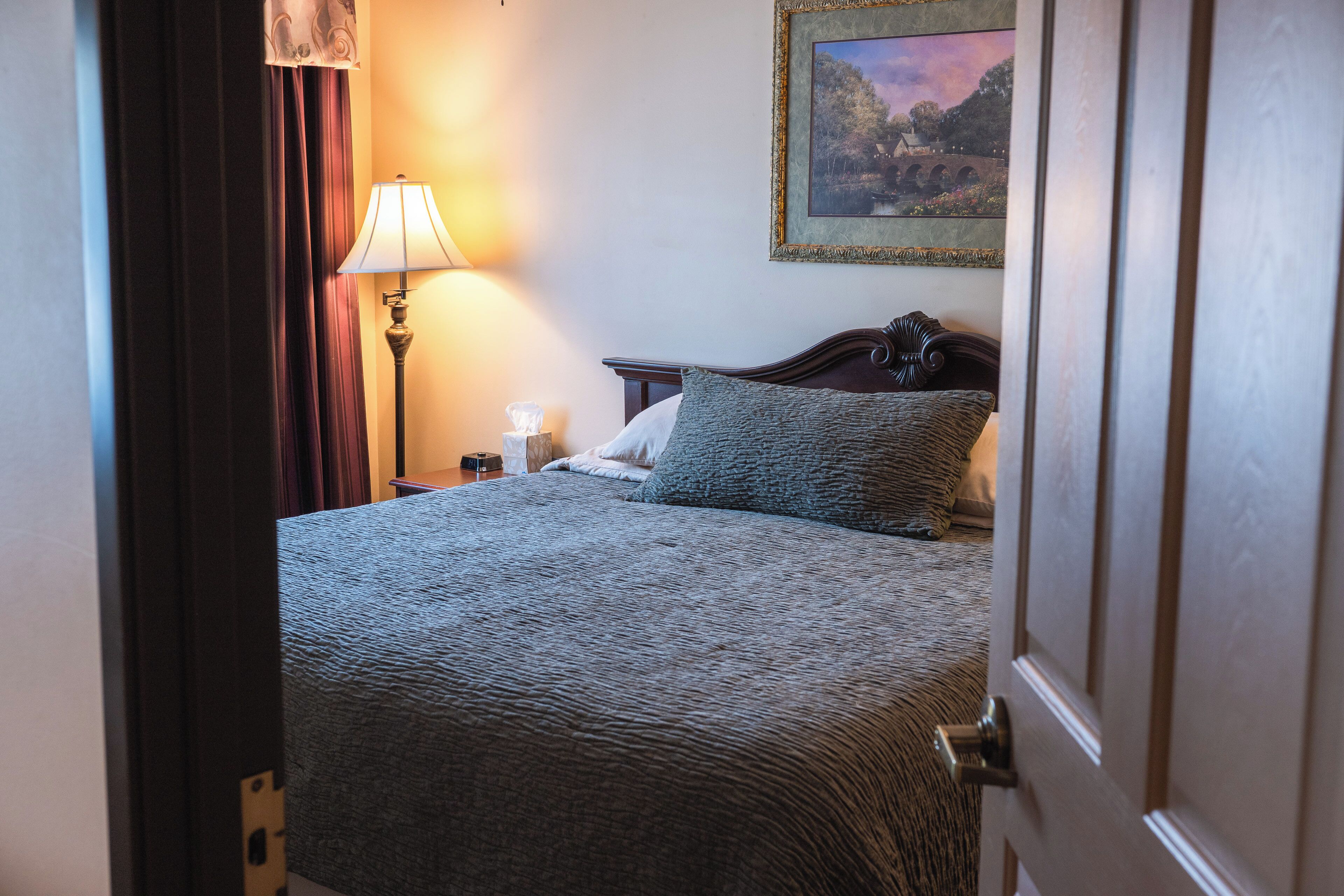 Une chambre d’hôtel avec un lit, une table de chevet, une lampe et un tableau au mur.