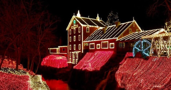 A building with multiple windows and a prominent chimney, surrounded by trees and decorated with lights. - Hearthstone Inn & Suites (Cedarville)