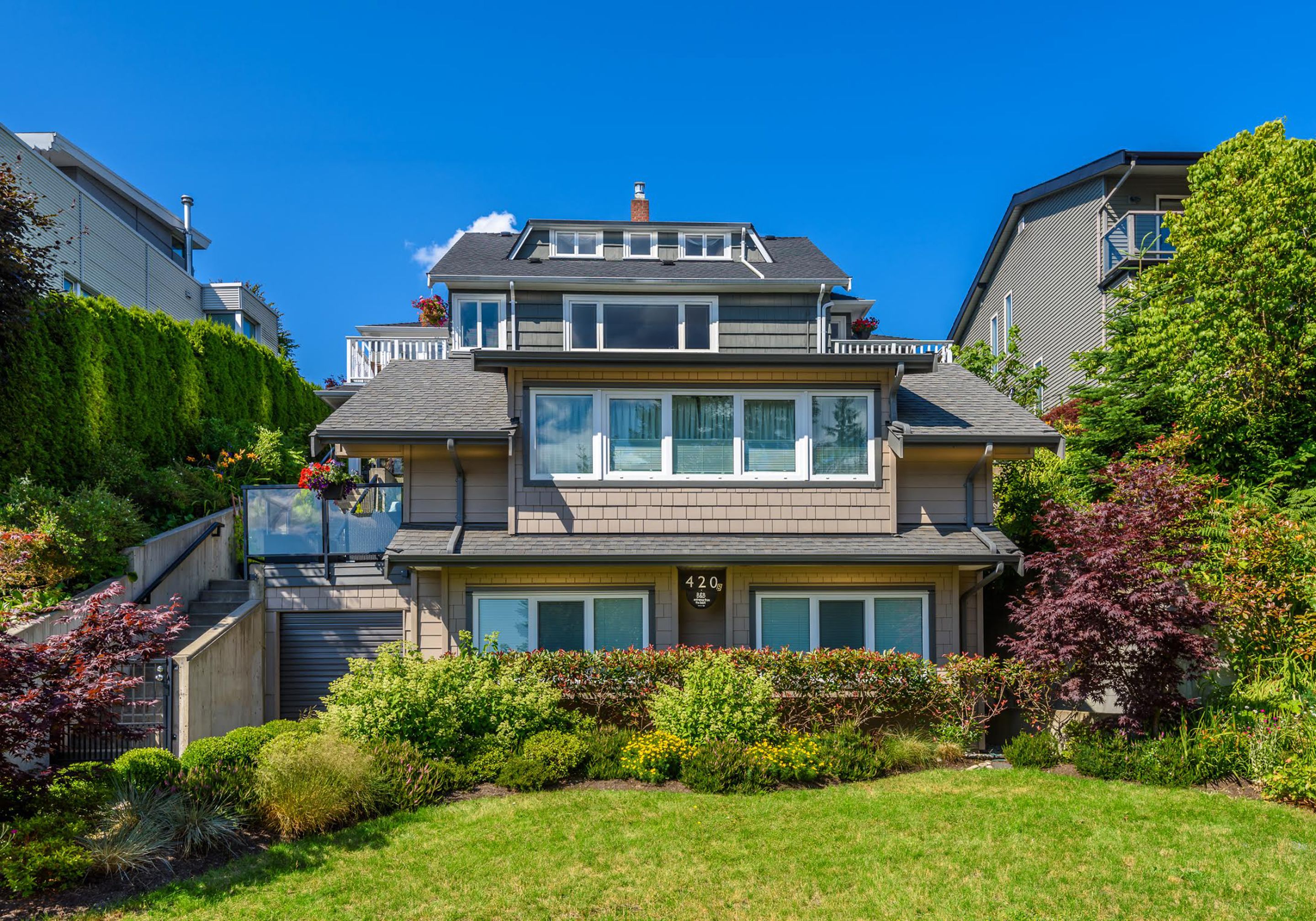 A two-story residential house with a front entrance, a visible garage, and a well-maintained garden.