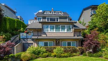 A two-story residential house with a front entrance, a visible garage, and a well-maintained garden.