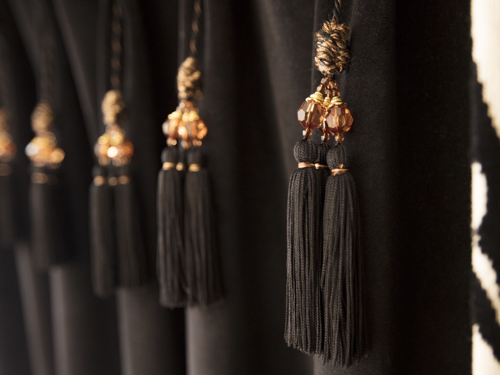 A close-up of black tassels hanging from a fabric surface.