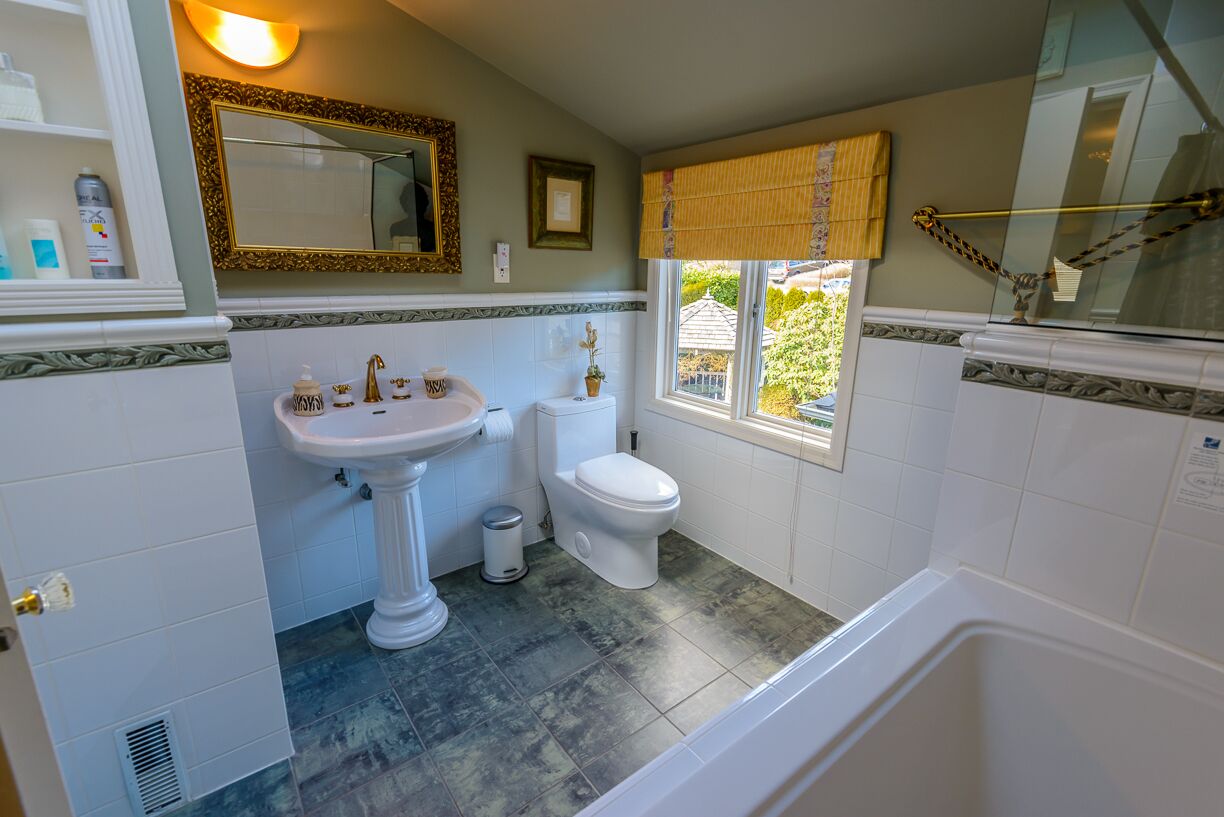 Une salle de bain avec un lavabo sur colonne, des toilettes et une baignoire.
