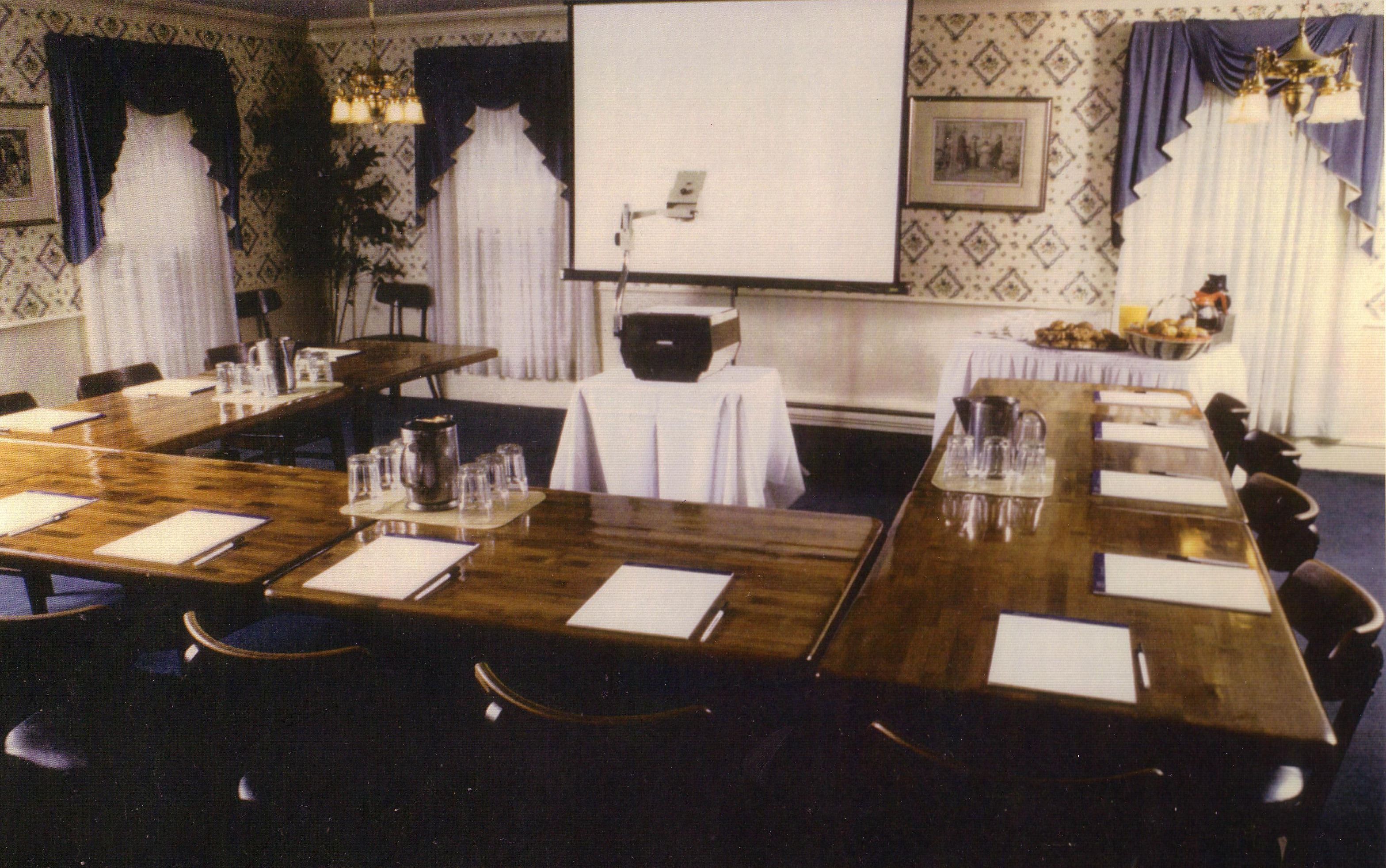 A conference room with a long table, chairs, a projector screen, and a whiteboard.