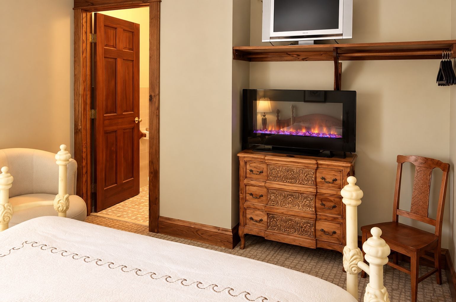 A bedroom with a bed, a wooden dresser, a television, and a chair.