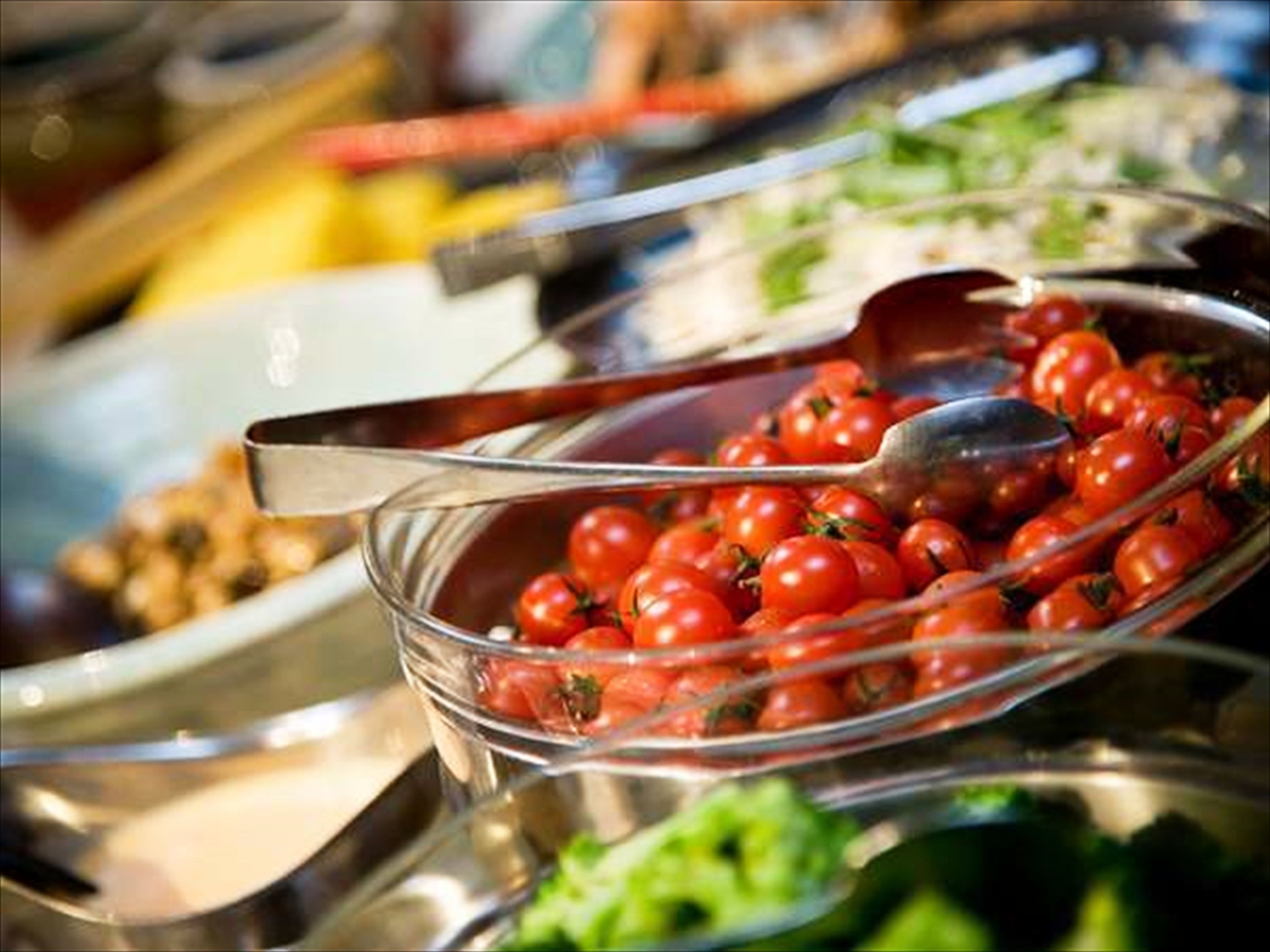 Un bufé con varios platos, incluyendo un tazón de tomates cherry.