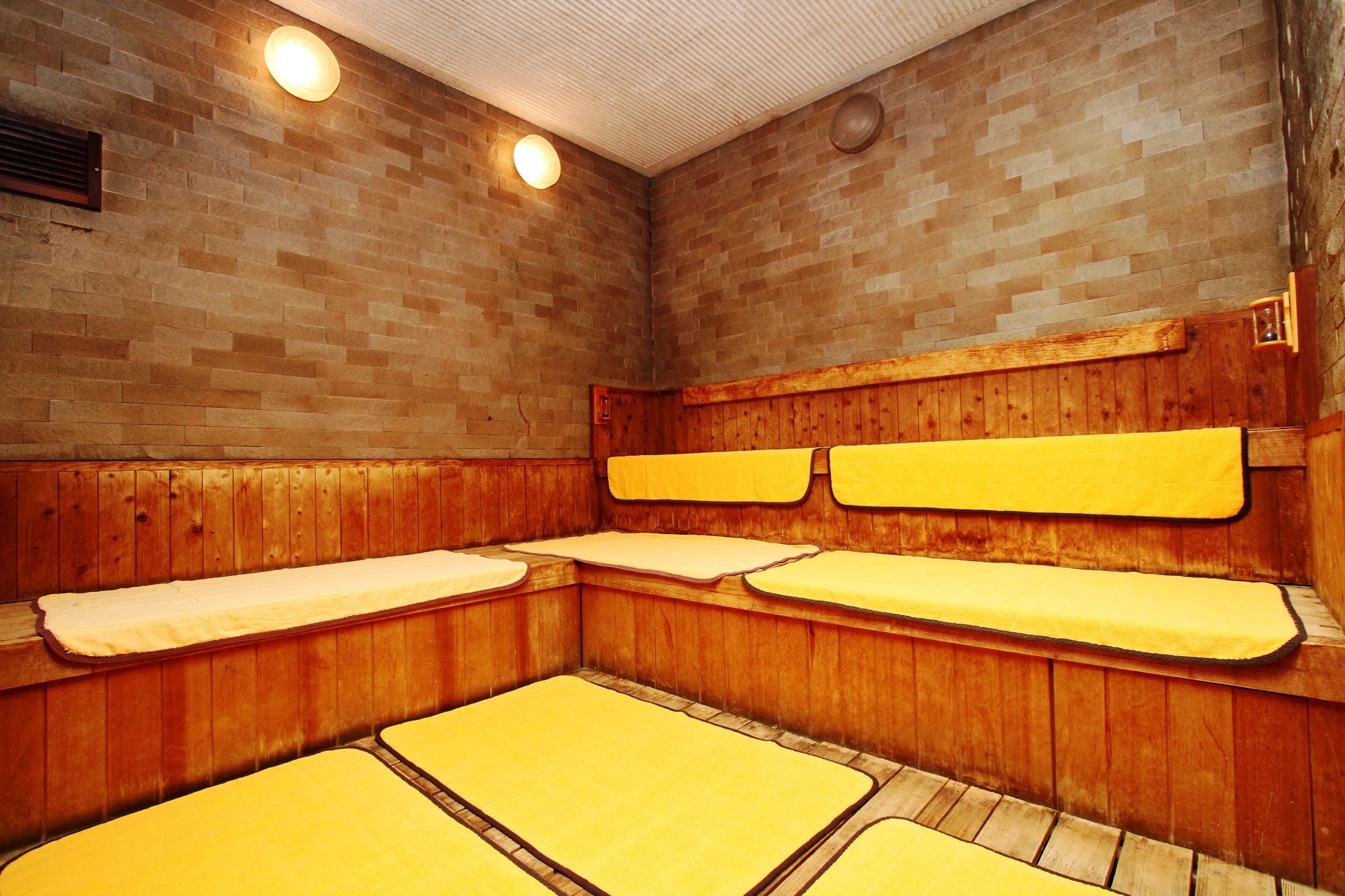 A sauna with wooden benches and a brick wall.