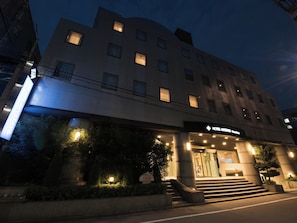 Un hotel con un diseño arquitectónico moderno, que presenta una entrada destacada con escalones y puerta de cristal.