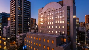 A modern high-rise building with multiple floors, large windows, and a prominent curved structure on the upper level. - HOTEL MYSTAYS Ueno East (Tokyo)