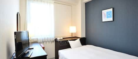Habitación de hotel con una cama, un escritorio con ordenador, una lámpara y un cuadro en la pared.