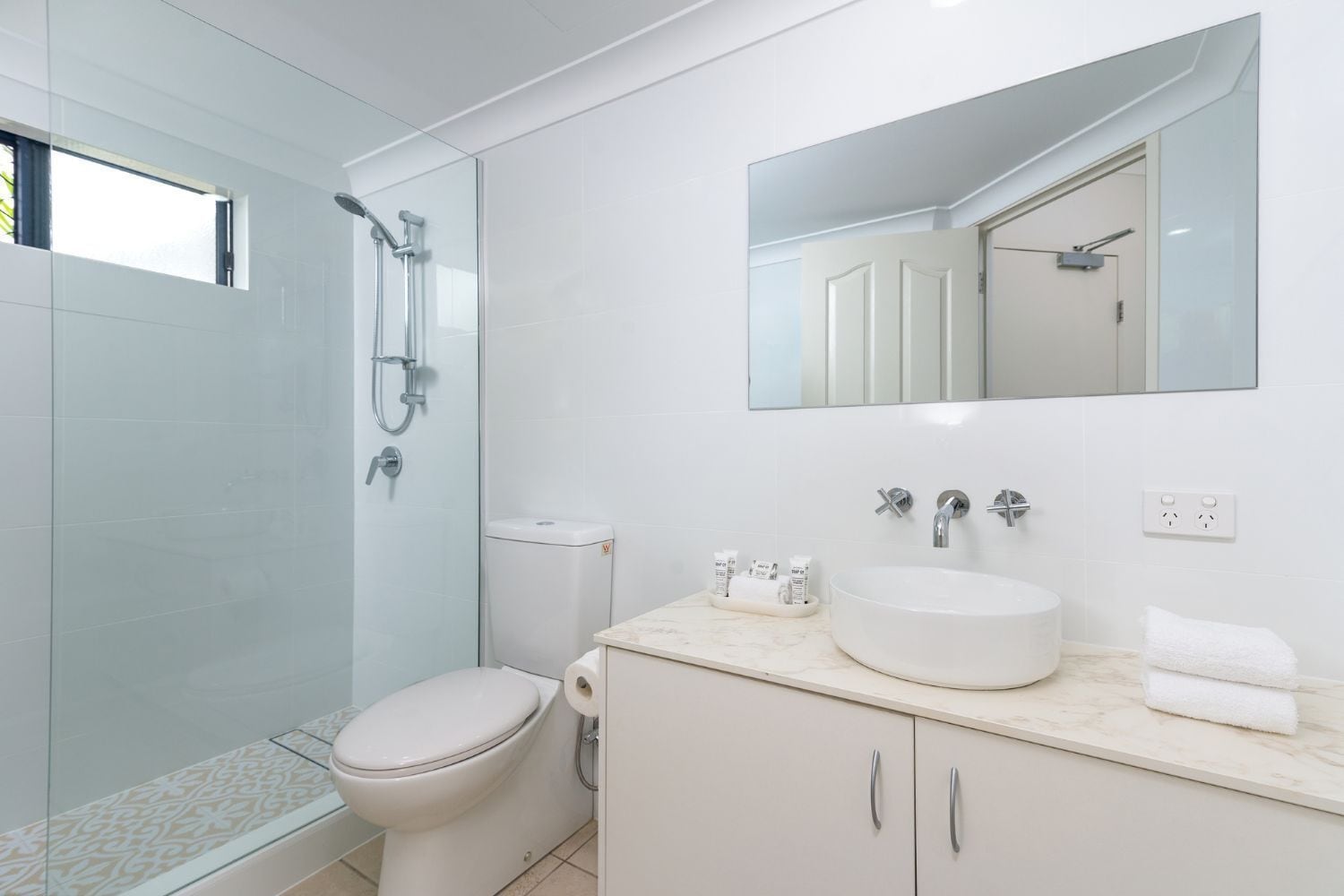 A modern bathroom with a toilet, shower, sink, and vanity.