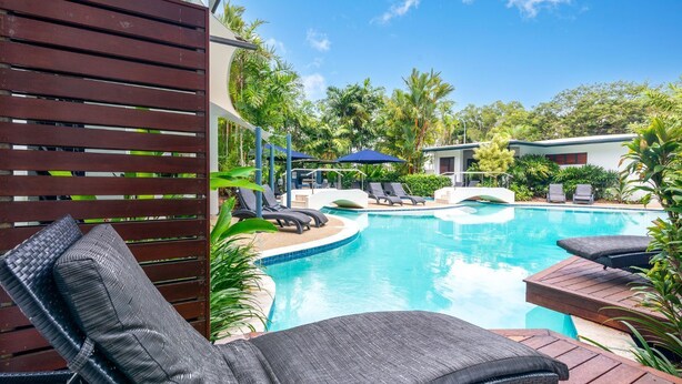 A pool area with lounge chairs, a wooden deck, and tropical plants. - Meridian Port Douglas - Adults only (Port Douglas)