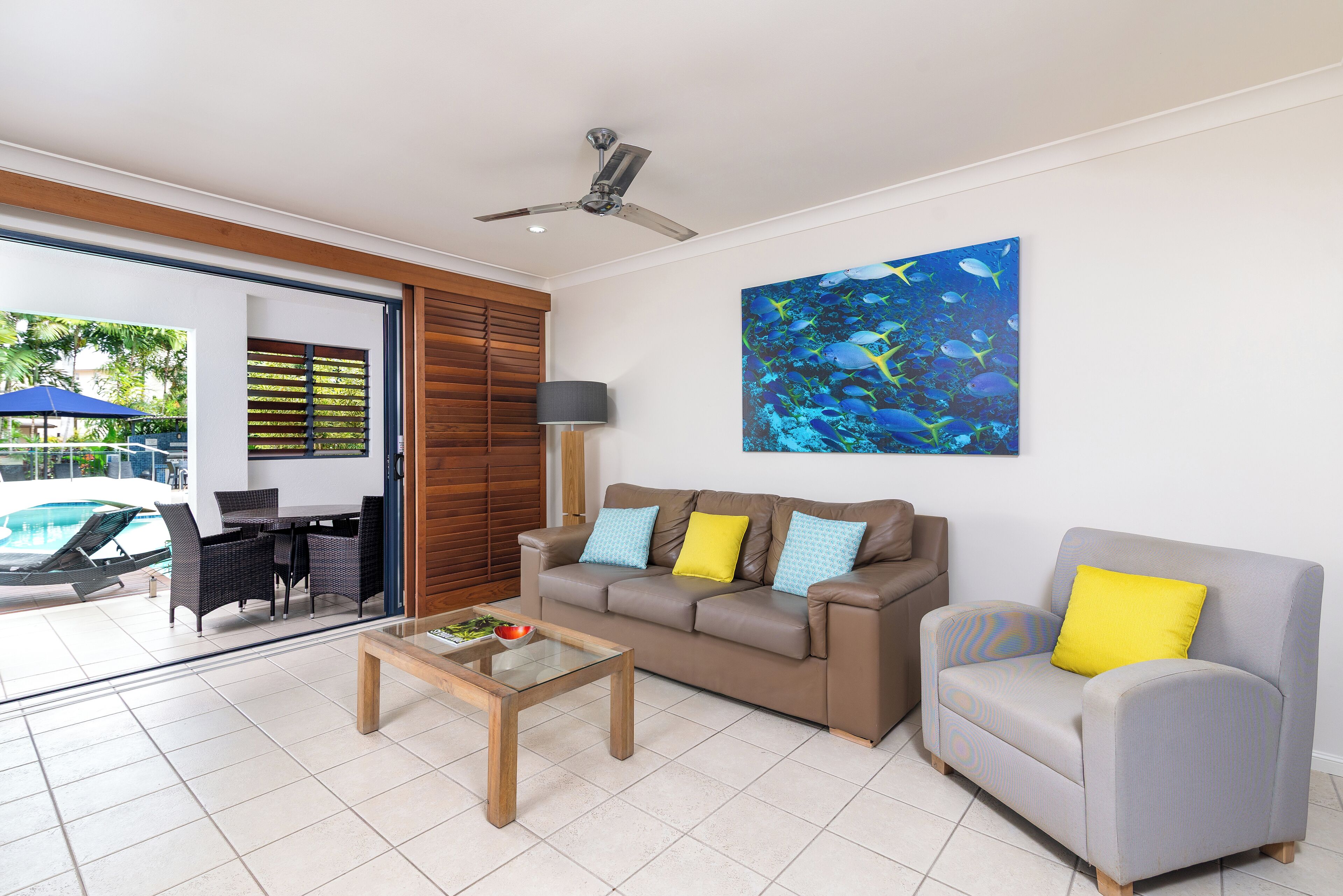 Una sala de estar moderna con un sofá, un sillón, una mesa de centro y un cuadro de peces en la pared.