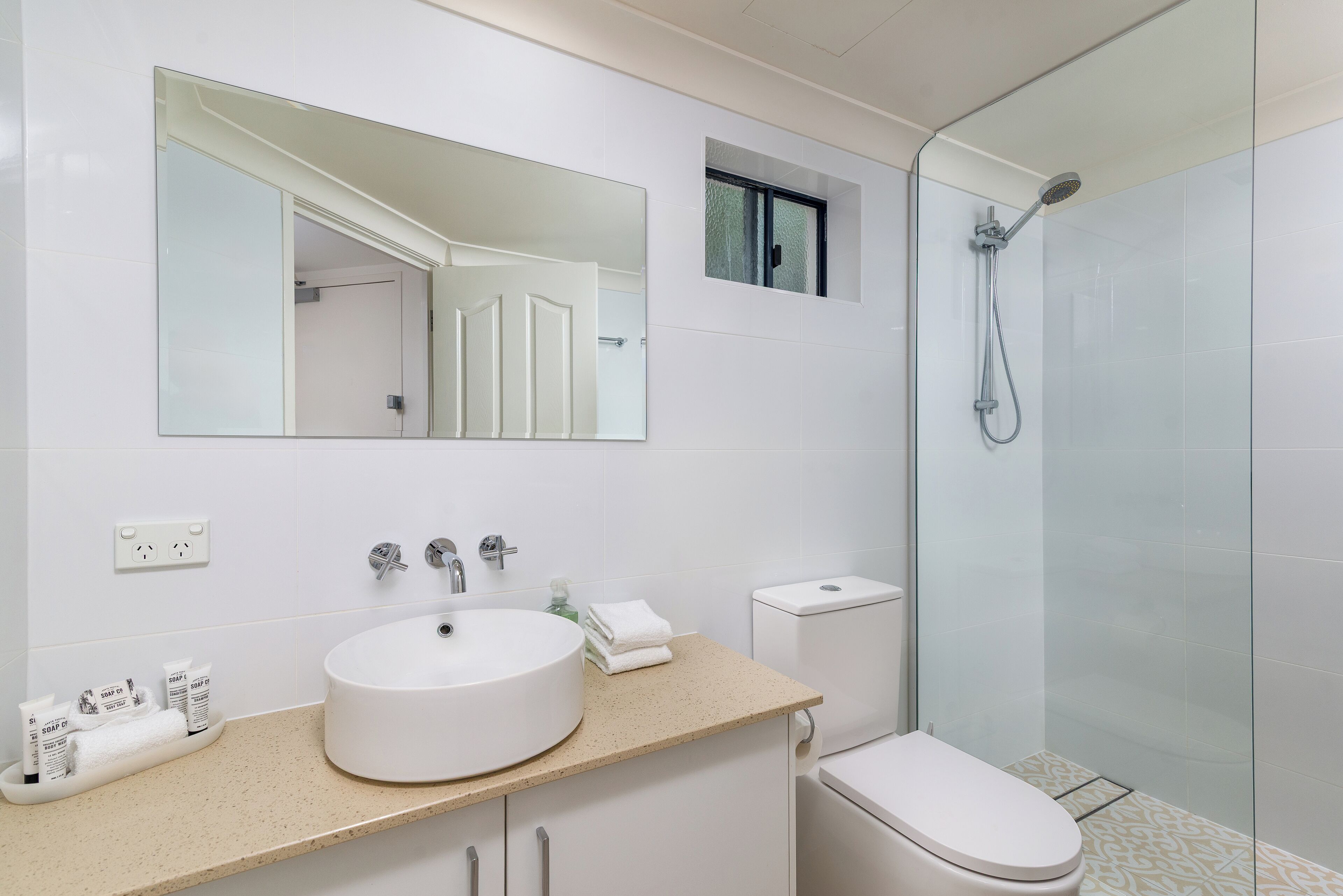 Een moderne badkamer met een grote spiegel, een wastafel, toilet en douche.