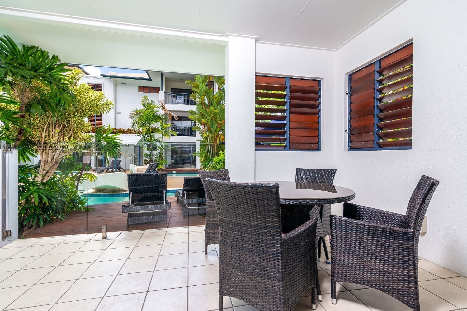 A patio area with wicker furniture, a pool, and a view of a building with balconies.