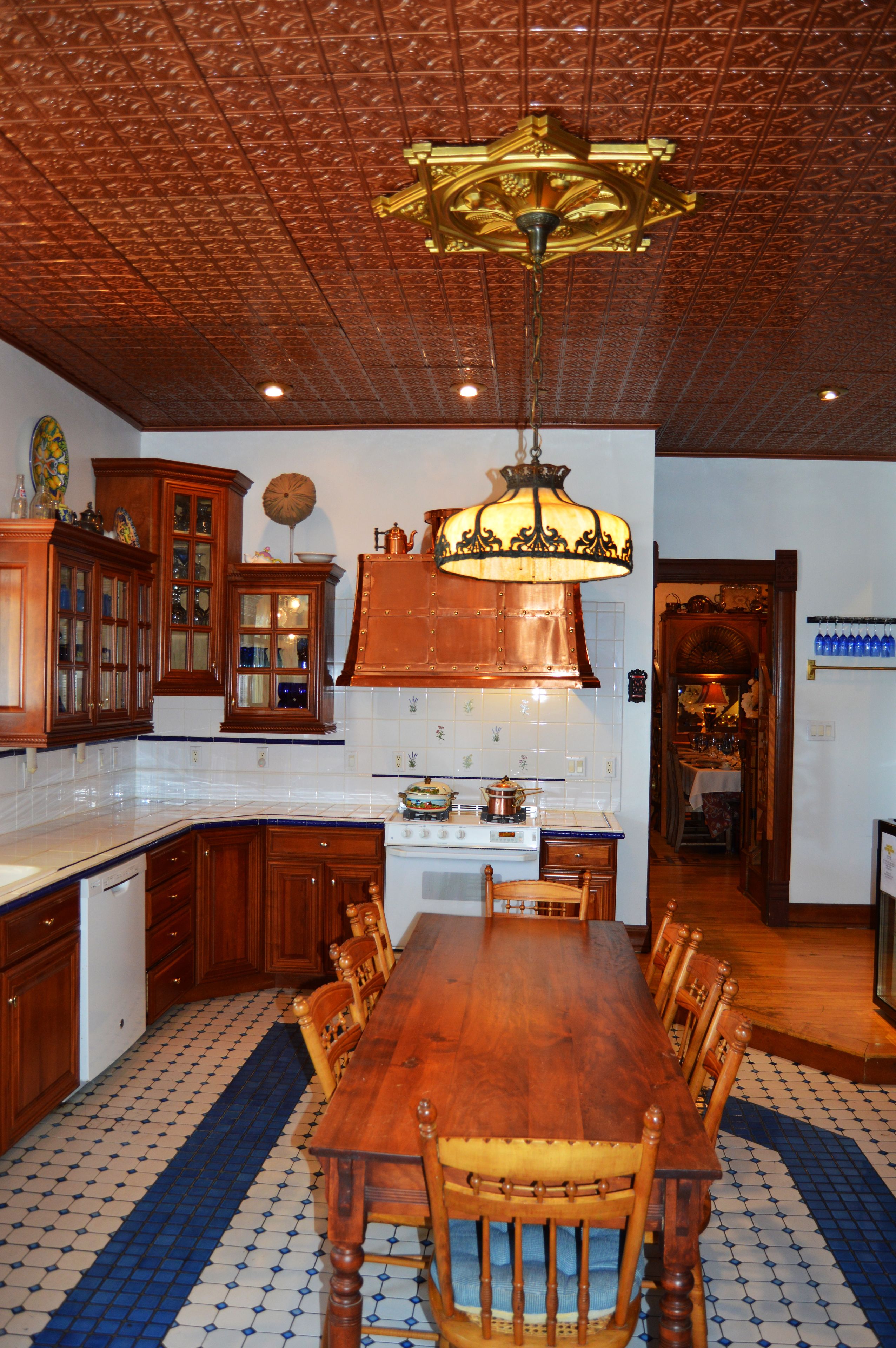 Une cuisine avec des meubles de rangement en bois, une grande table à manger et un luminaire suspendu.
