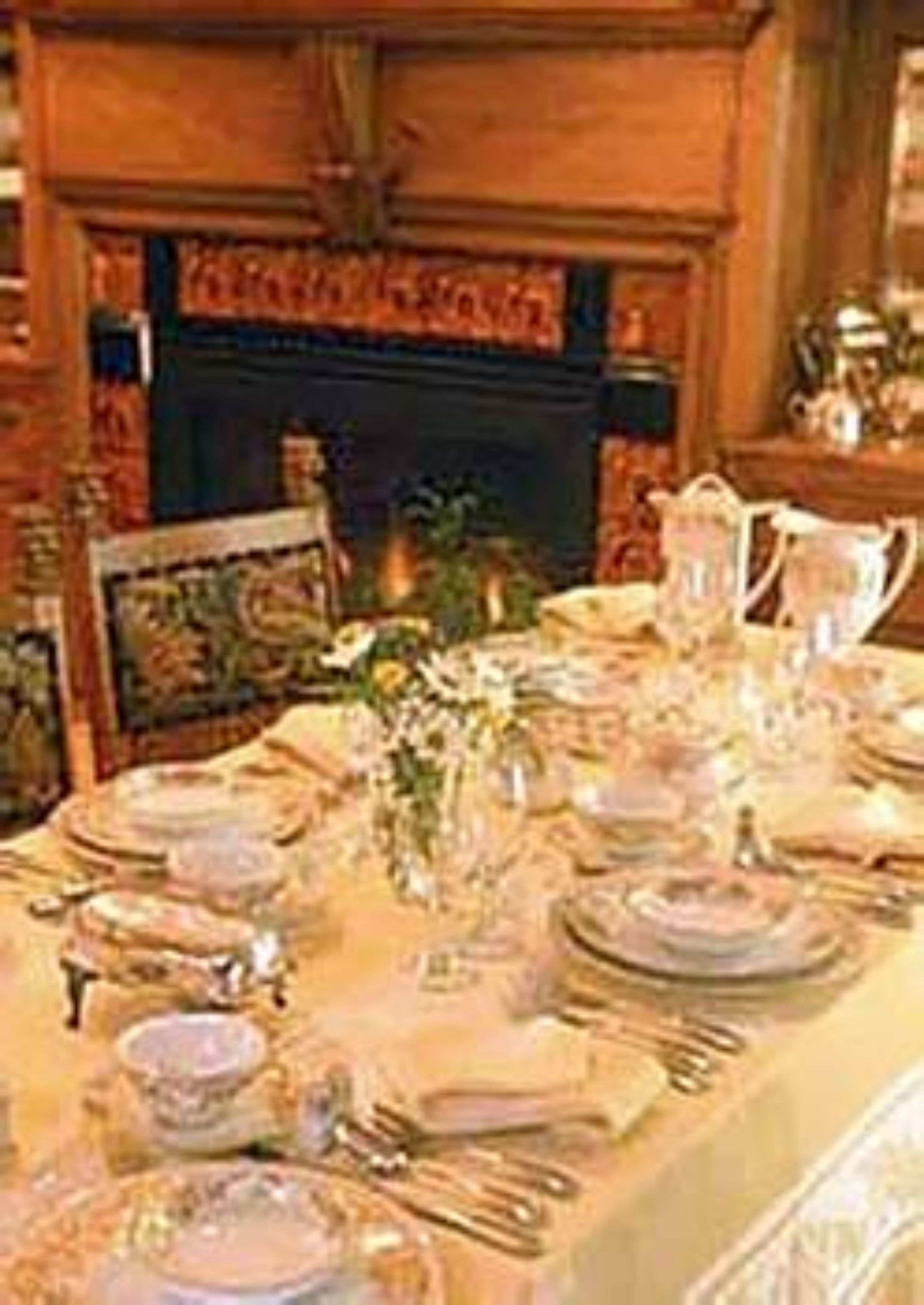 Un comedor con chimenea, una mesa dispuesta para cuatro personas y un cuadro en la pared.