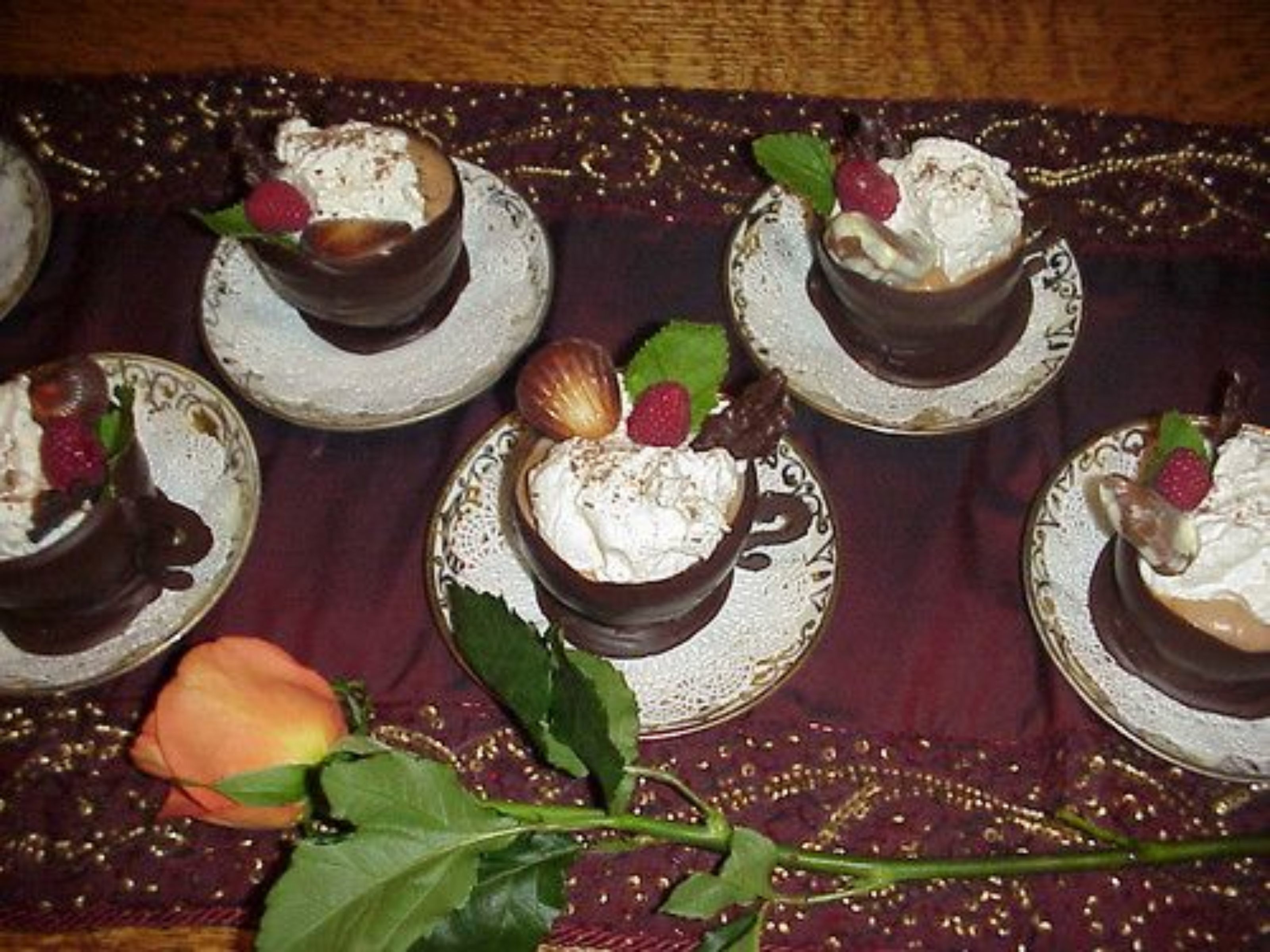 Una exhibición de postres con copas de chocolate cubiertas de crema batida y adornadas con frutas y nueces.