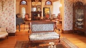 A spacious living room with a large armchair, a coffee table, and a chandelier.