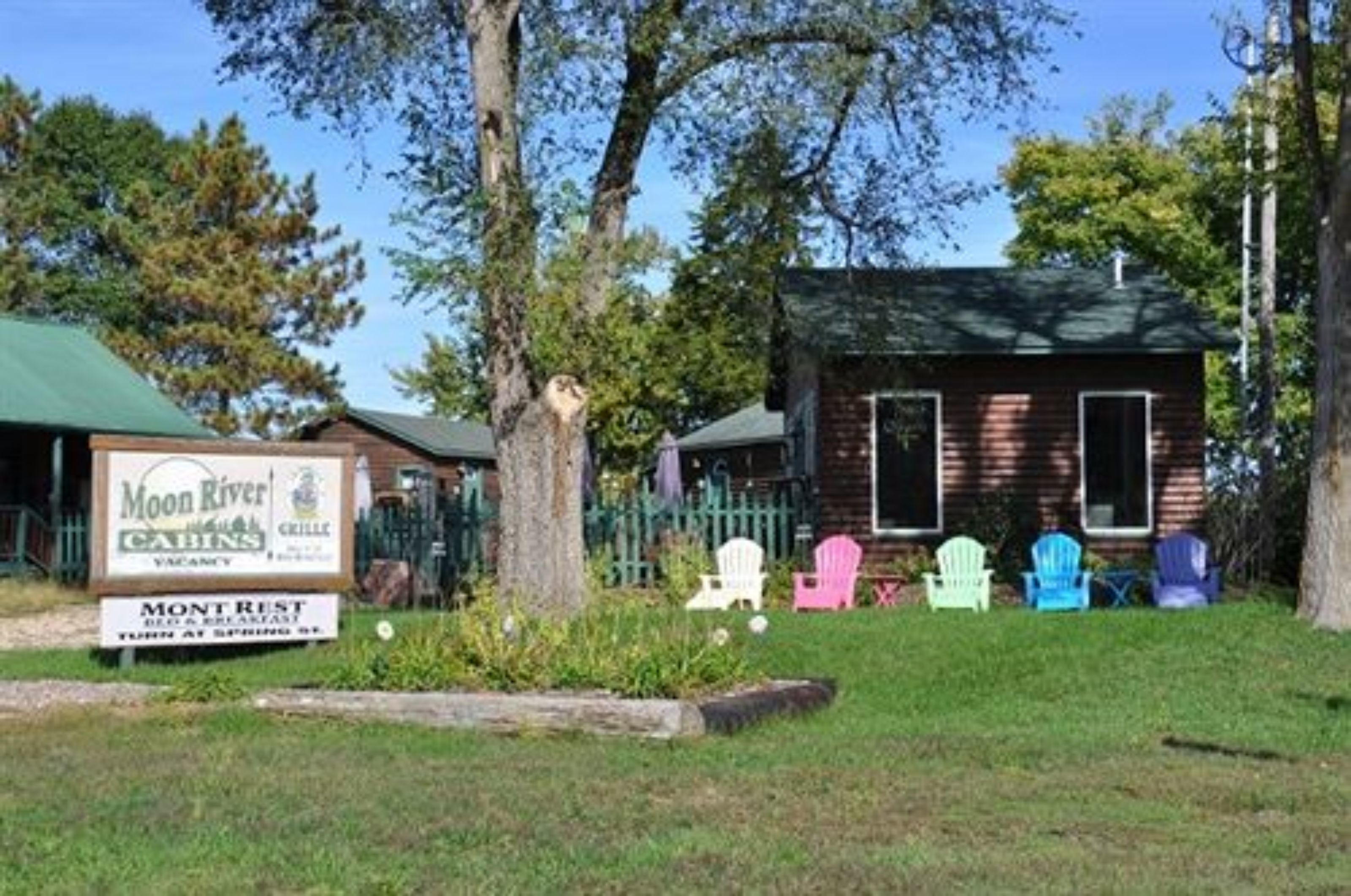 A cabin-style building with a green roof, surrounded by trees and a sign for Moon River Cabins.
