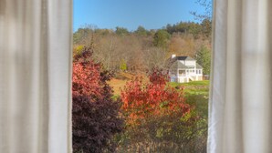 A house with a large front lawn, surrounded by trees with autumn foliage. - The Kittle House Inn (Chappaqua)