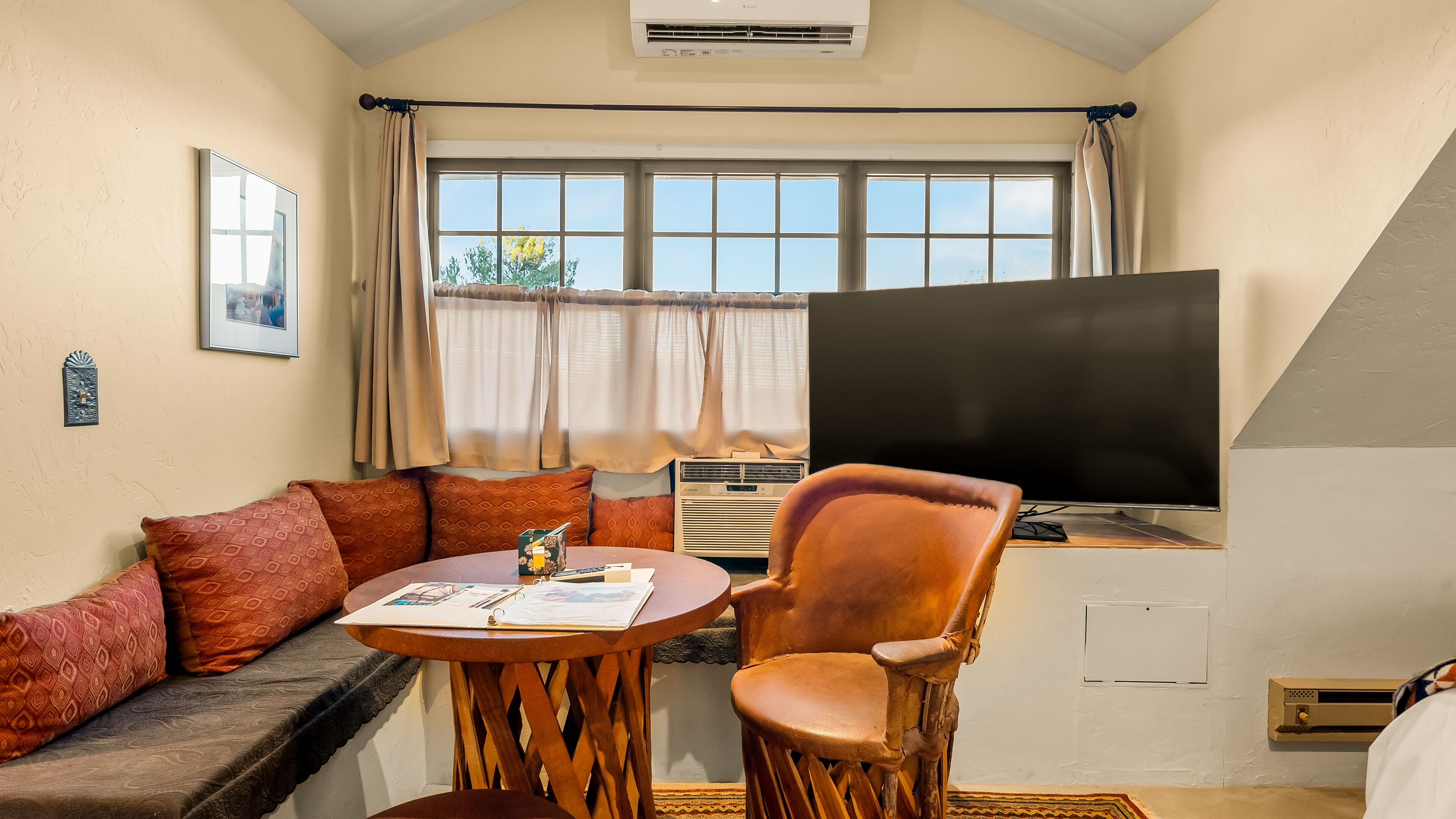 Una sala de estar acogedora con un sofá, una silla, una mesita y un televisor.