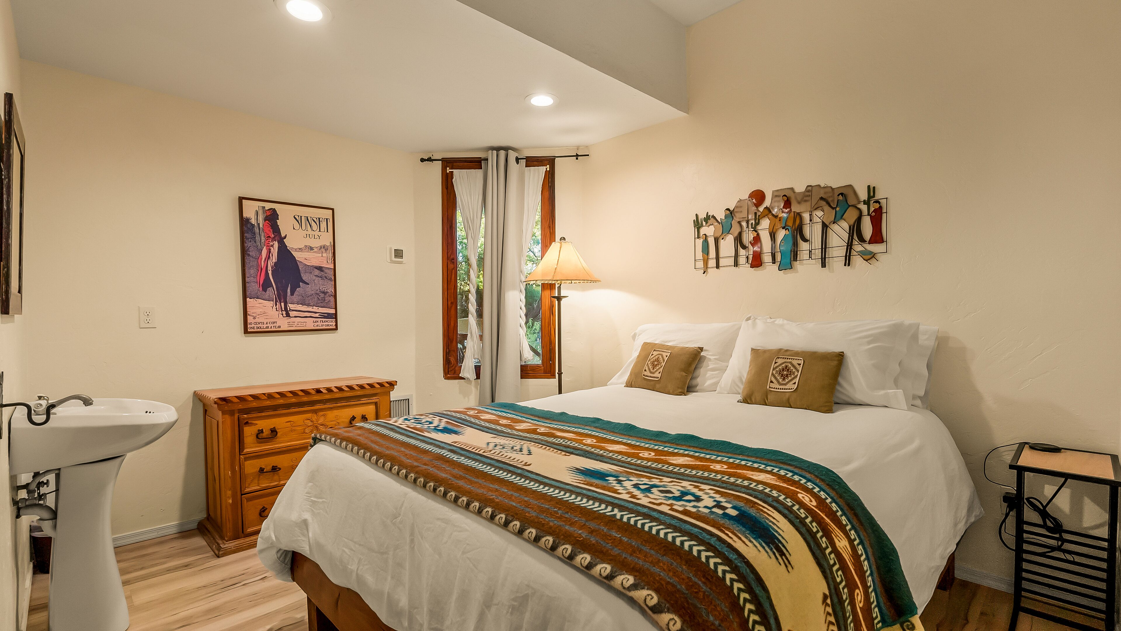 A bedroom with a bed, bedside table, lamp, and a wall with decorative items.
