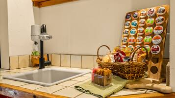 A kitchen with a sink, a faucet, a wooden board with food containers, a basket of bread, and a rolling pin.