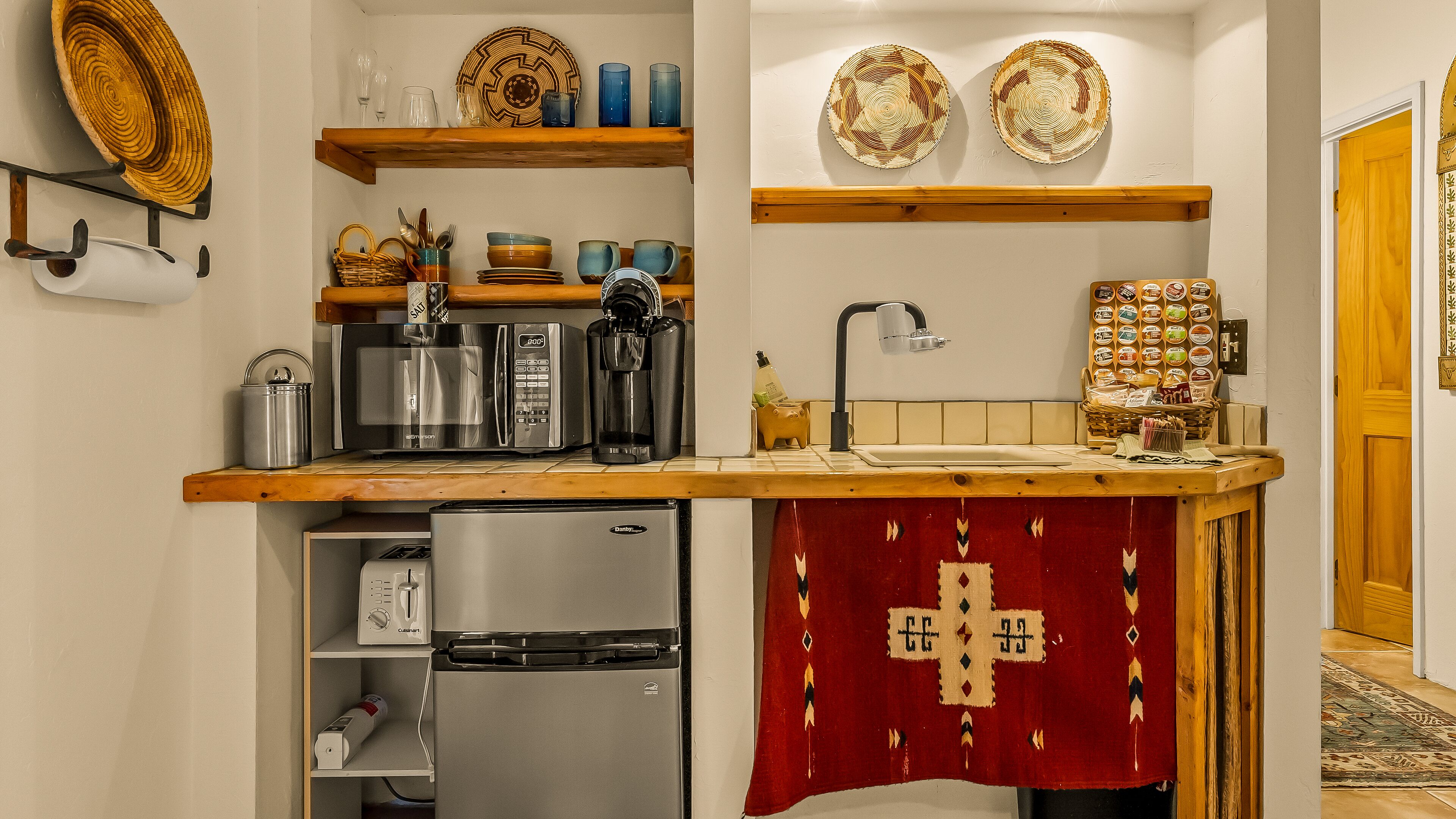 Cozinha com bancada de madeira, eletrodomésticos de aço inoxidável e um pano estampado vermelho sobre a pia.