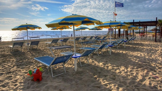 A beach with rows of sun loungers and umbrellas, a lifeguard tower, and a clear view of the ocean. - Hotel Le Tegnue (Chioggia)