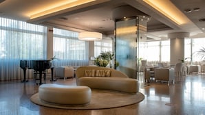 A modern lobby with a piano, sofas, and a large column. - Hotel Le Tegnue (Chioggia)