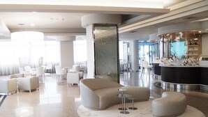 A modern lobby with a central seating area, a reception desk, and a bar. - Hotel Le Tegnue (Chioggia)