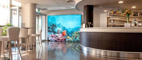 A modern lobby with a curved reception desk, seating area, and a large digital aquarium display.