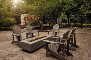 An outdoor seating area with Adirondack chairs and a fire feature. - Courtyard by Marriott Hamilton (Hamilton)