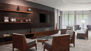 Un salon moderne avec un téléviseur à écran plat, des meubles en bois et une table basse en verre.