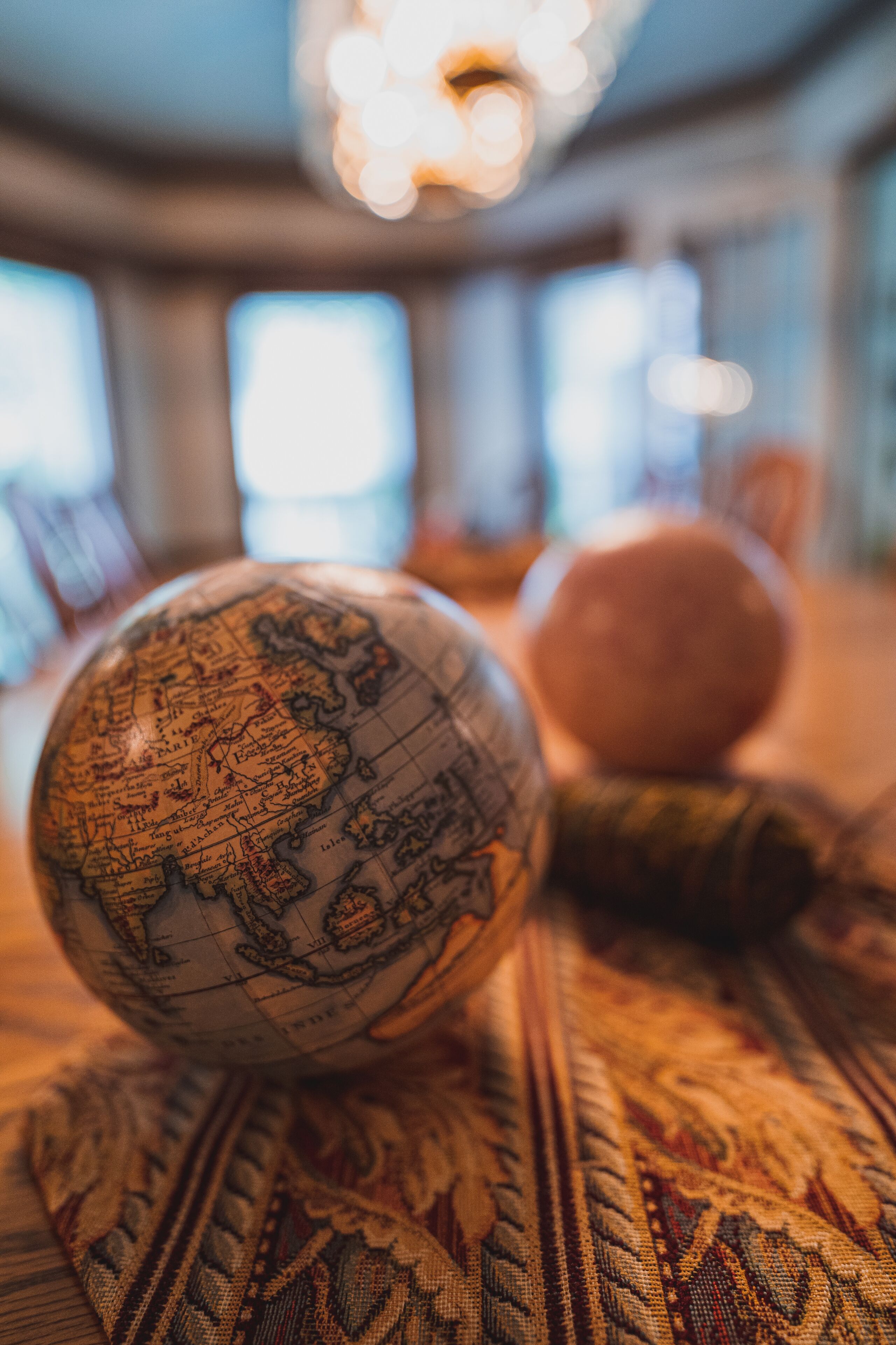 A globe and a round object on a patterned tablecloth.