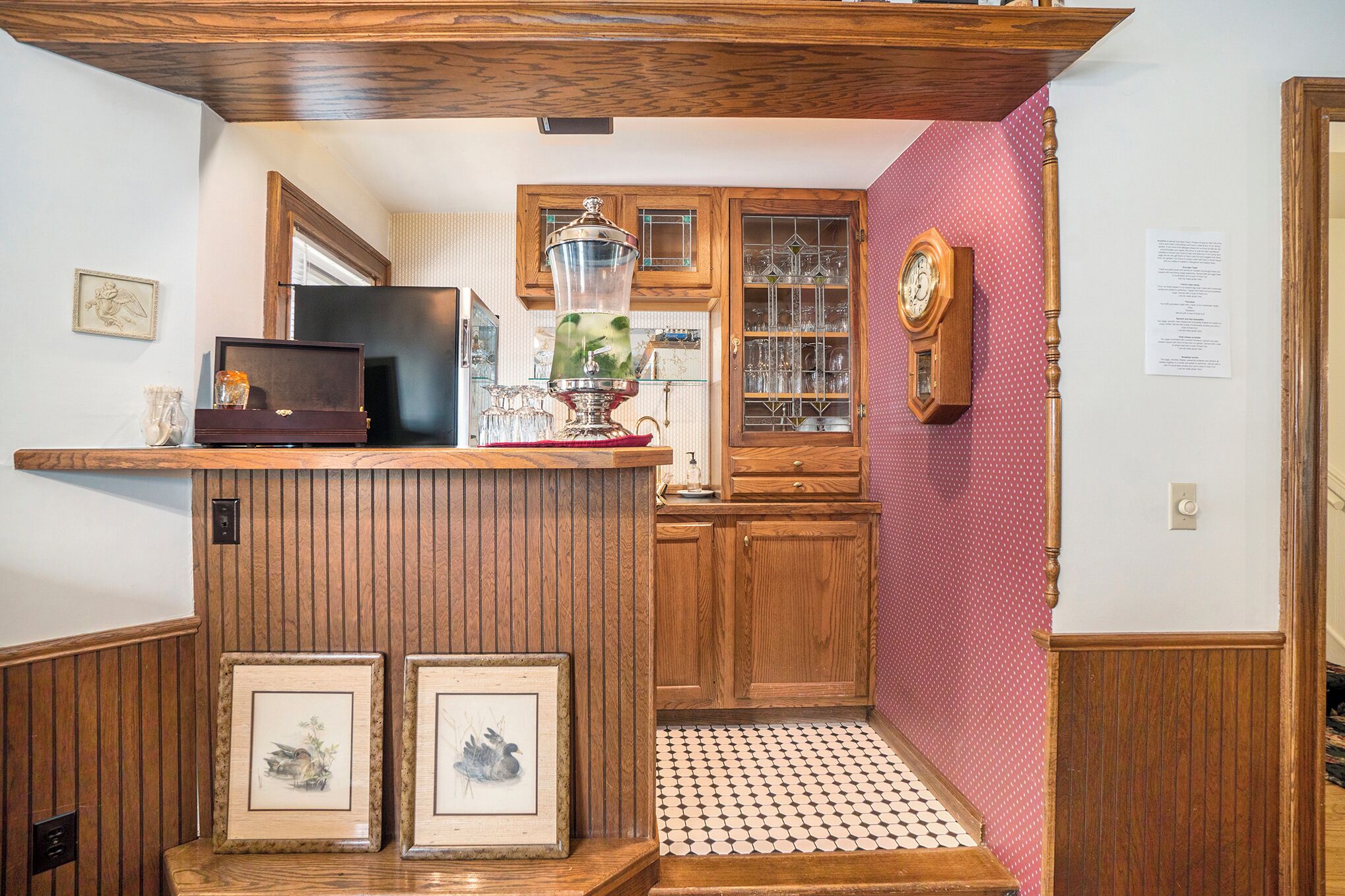 Una cocina con armarios de madera, encimera de madera, una radio antigua y cuadros enmarcados.
