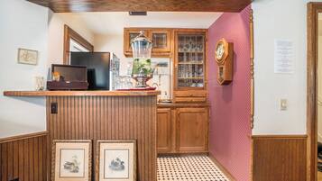 Une cuisine avec des meubles de rangement en bois, un plan de travail en bois, une radio ancienne et des tableaux encadrés.