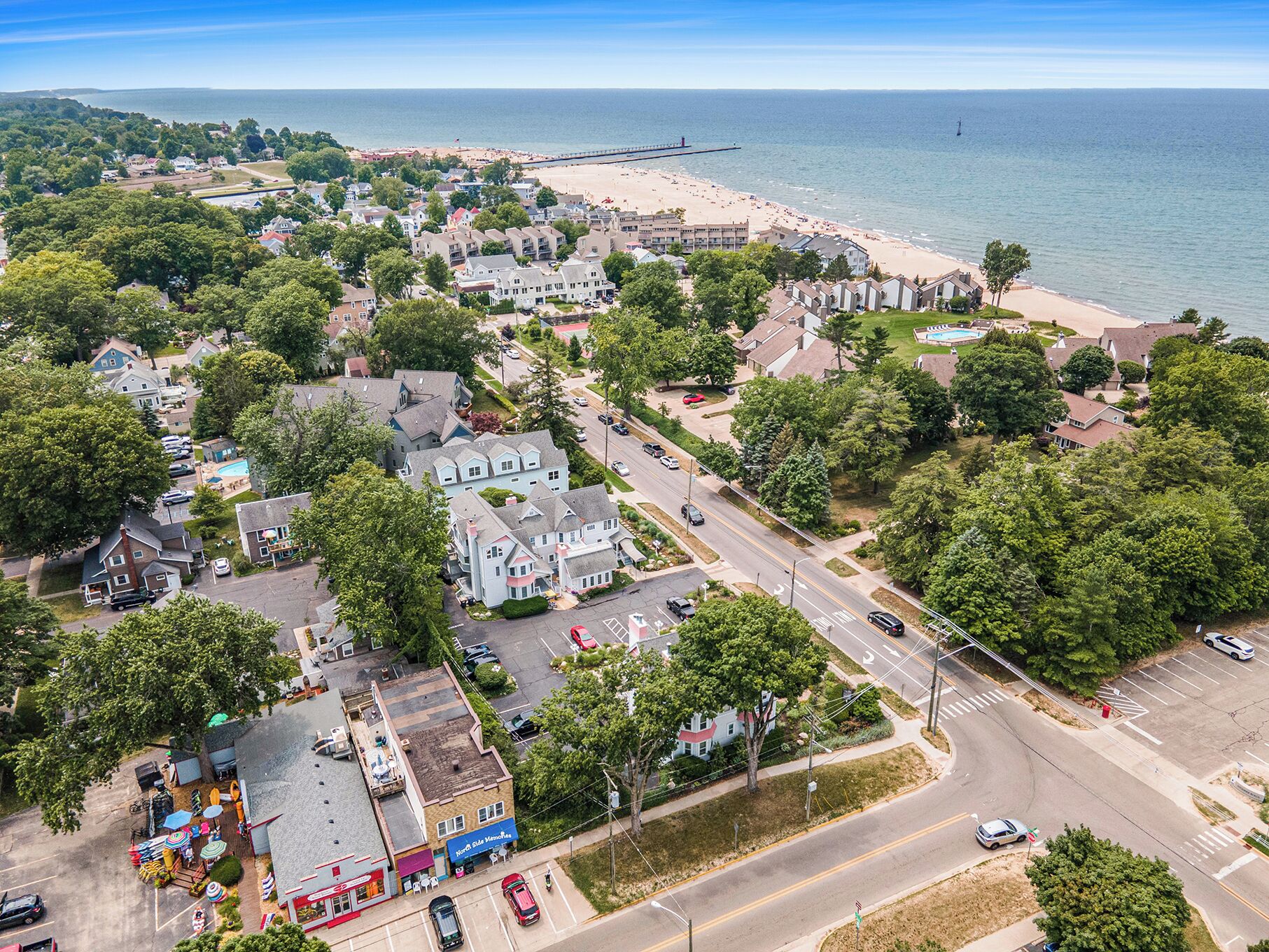 An aerial view of a coastal town with a beach, residential areas, and a prominent building with a sign reading "North Coast Main Road."