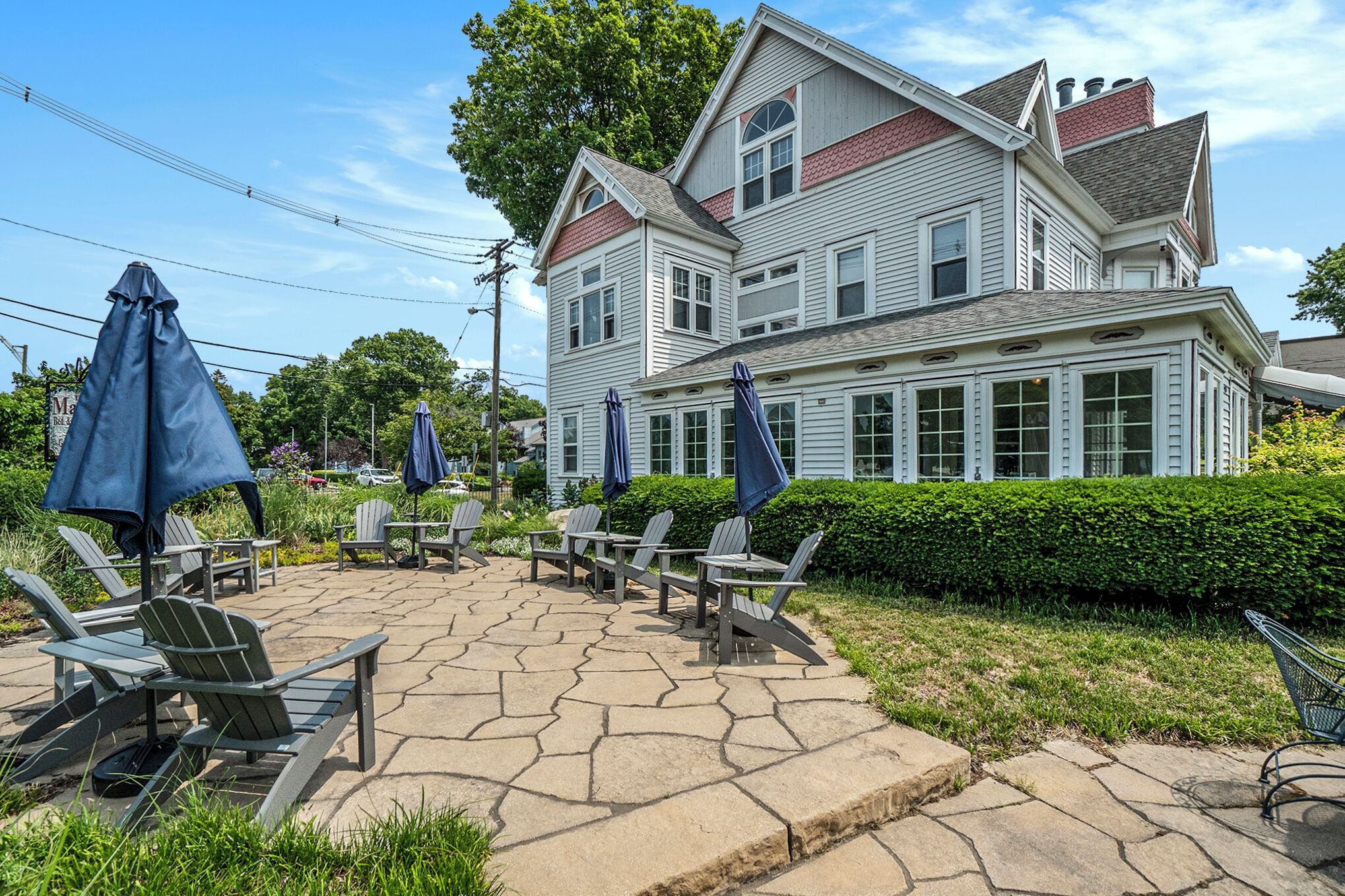 A two-story building with a stone patio, outdoor seating, and umbrellas.