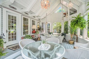 A covered porch with wicker furniture, a glass table, and potted plants. - Yelton Manor Bed & Breakfast (South Haven)